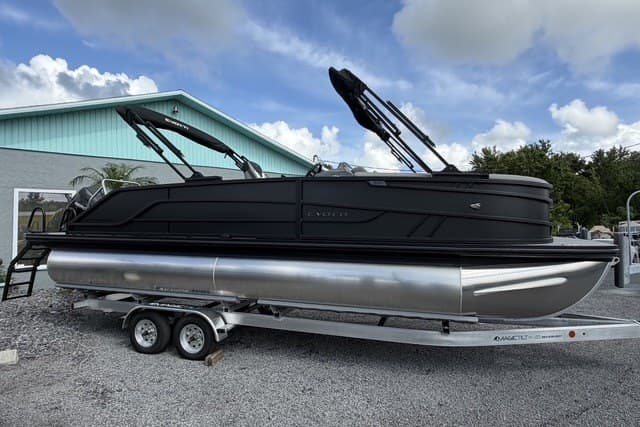 2027 Evotti 523CS pontoon boat on trailer, parked outdoors under cloudy sky.