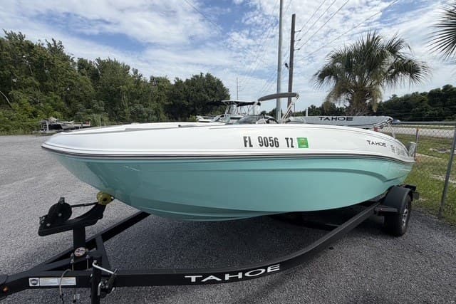 2025 Tahoe T18 boat on trailer, parked outdoors with trees and palm in background.