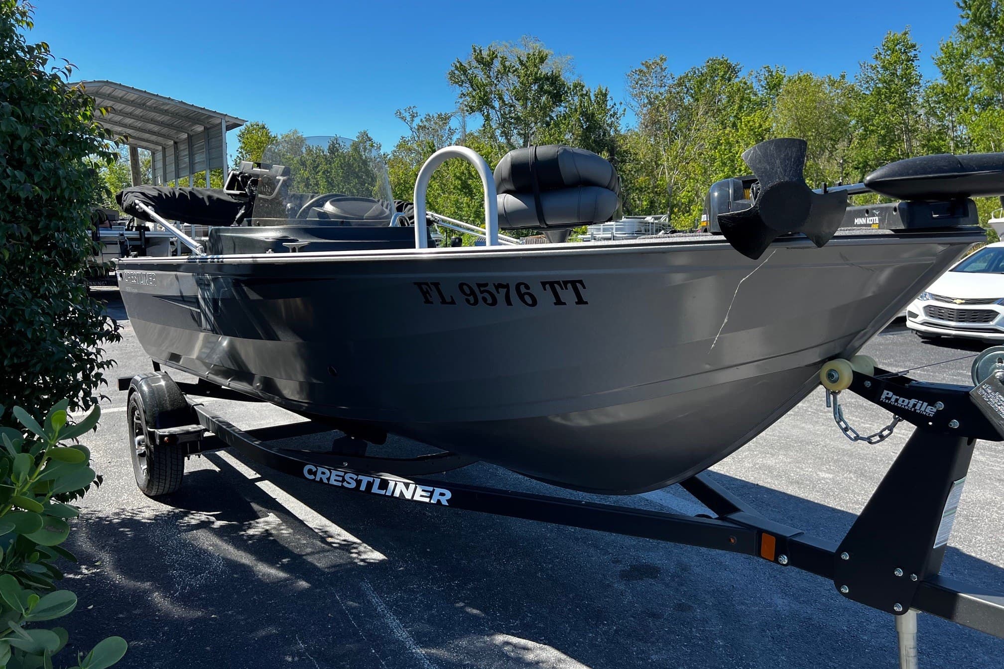 2023 Crestliner 1600 Vision boat on trailer, parked outdoors with trees in background.
