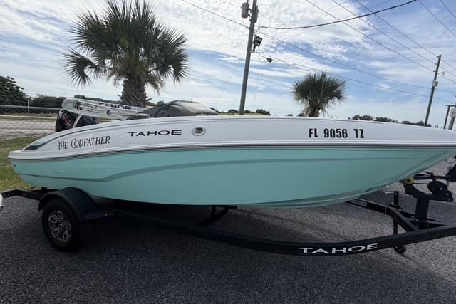 2025 Tahoe T18 boat on trailer, parked outdoors with palm trees in background.