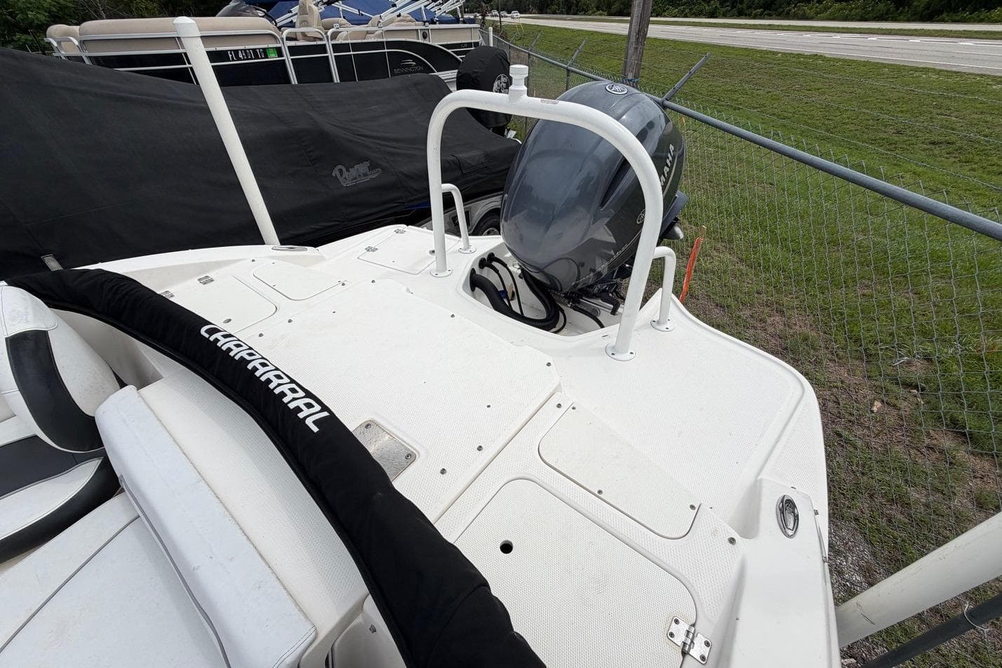 2020 Chaparral 196 SSi boat with outboard motor, docked near a fence.