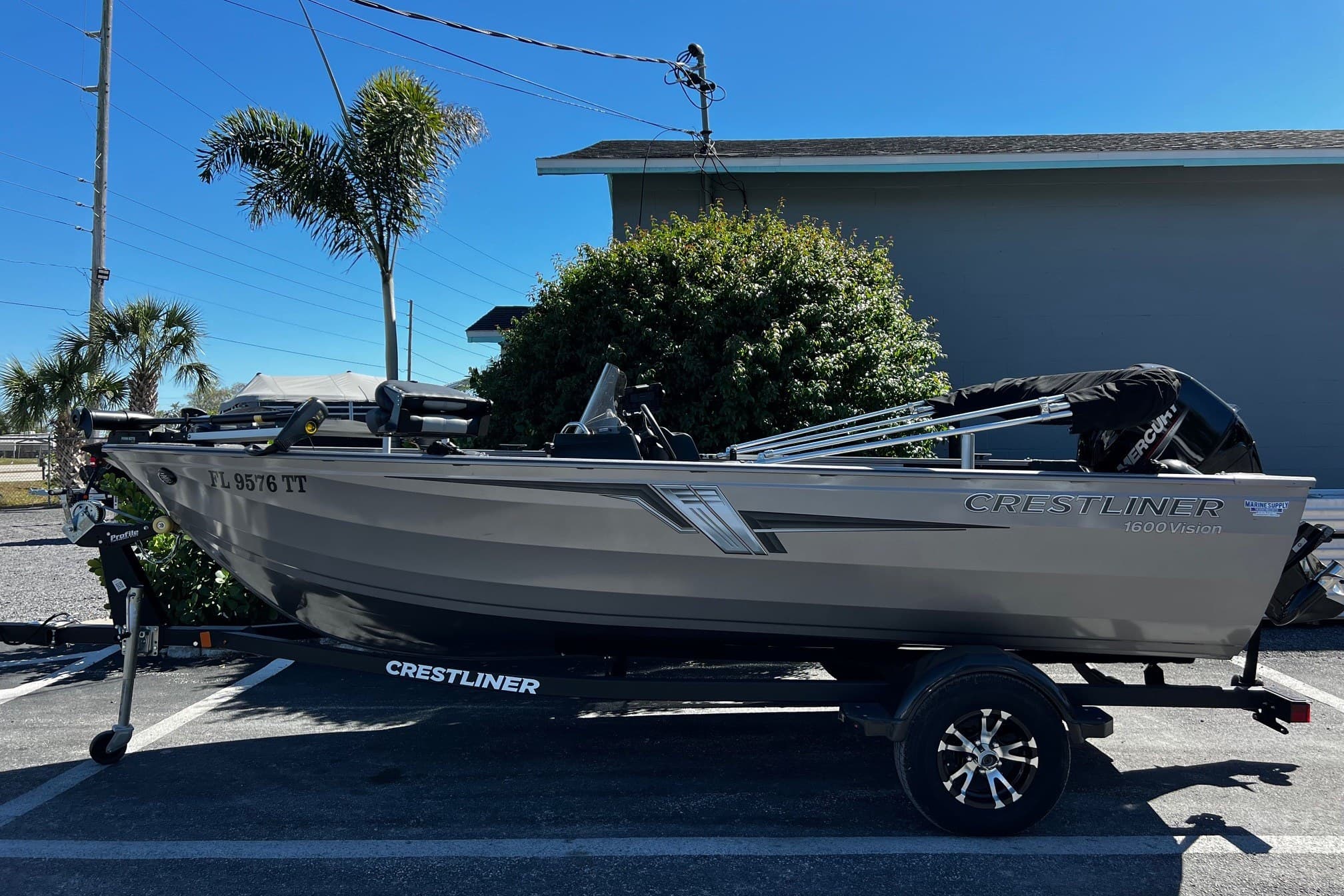 2023 Crestliner 1600 Vision boat on trailer, parked outdoors with palm trees.